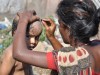 Eine Frau rasiert Ihrem Kind den Kopf auf der Straße