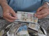 Er hält 10 Omanische Rial in der Hand (20 Euro)